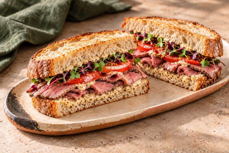 Sourdough sandwich with roast beef and colourful microgreens on a handmade pottery board